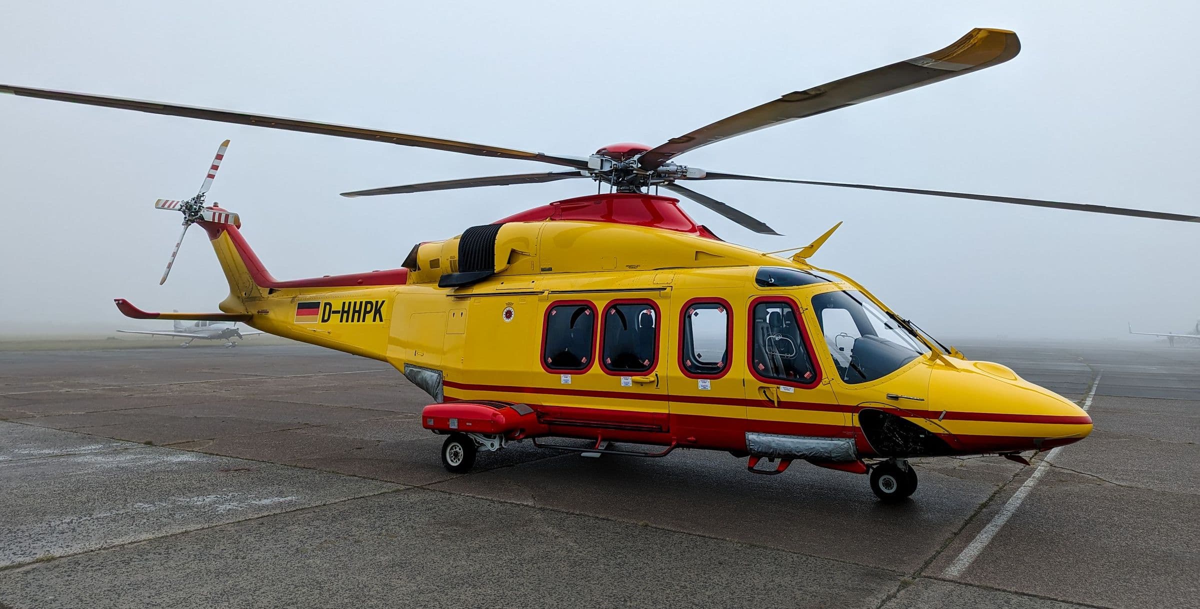 Twin-engine helicopter parked on a fog-covered airport ramp