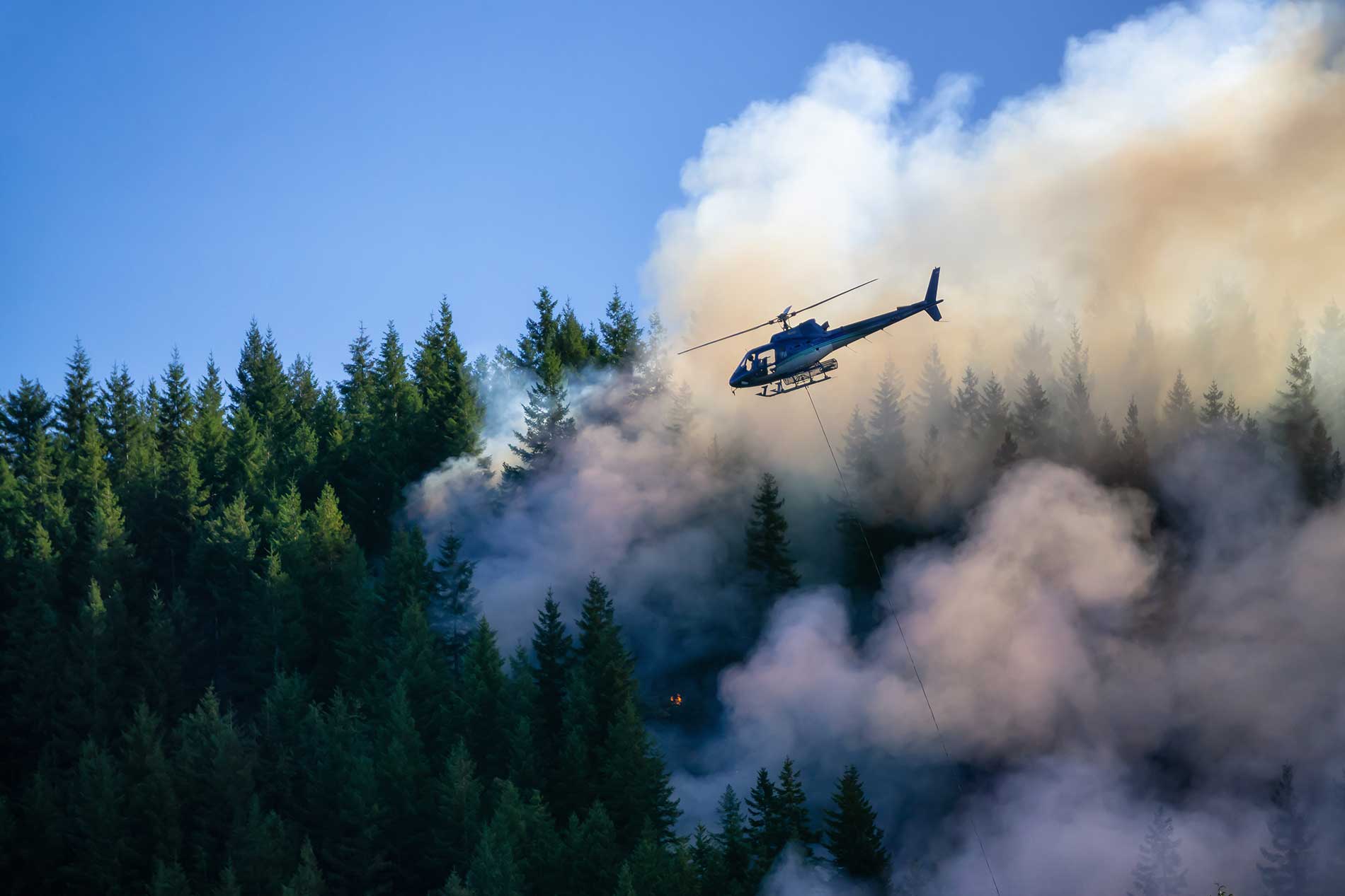 Helicopter flying over a wildfire during aerial firefighting operations