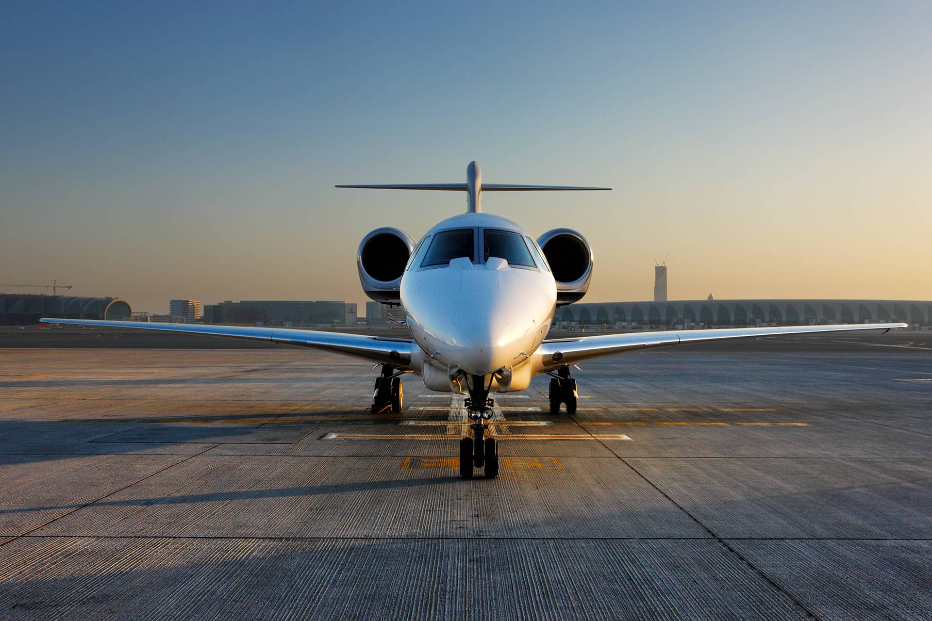 Corporate jet parked on an airport ramp at sunset